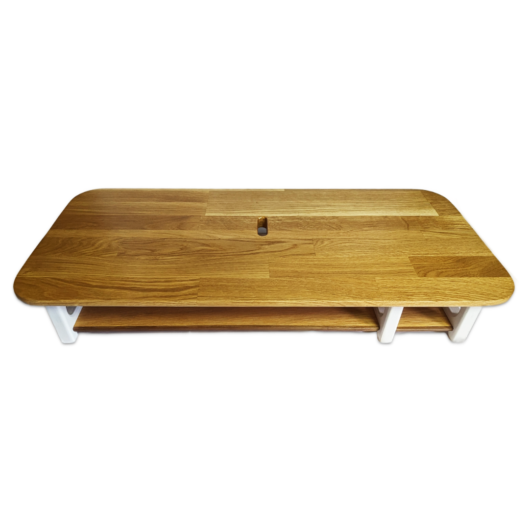 A wooden monitor stand with a capsule-shaped hole in the centre, a shelf below and white painted legs.