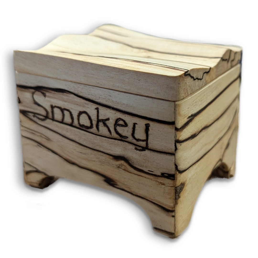 A wavy-edged box made from white wood with black lines running through the grain.