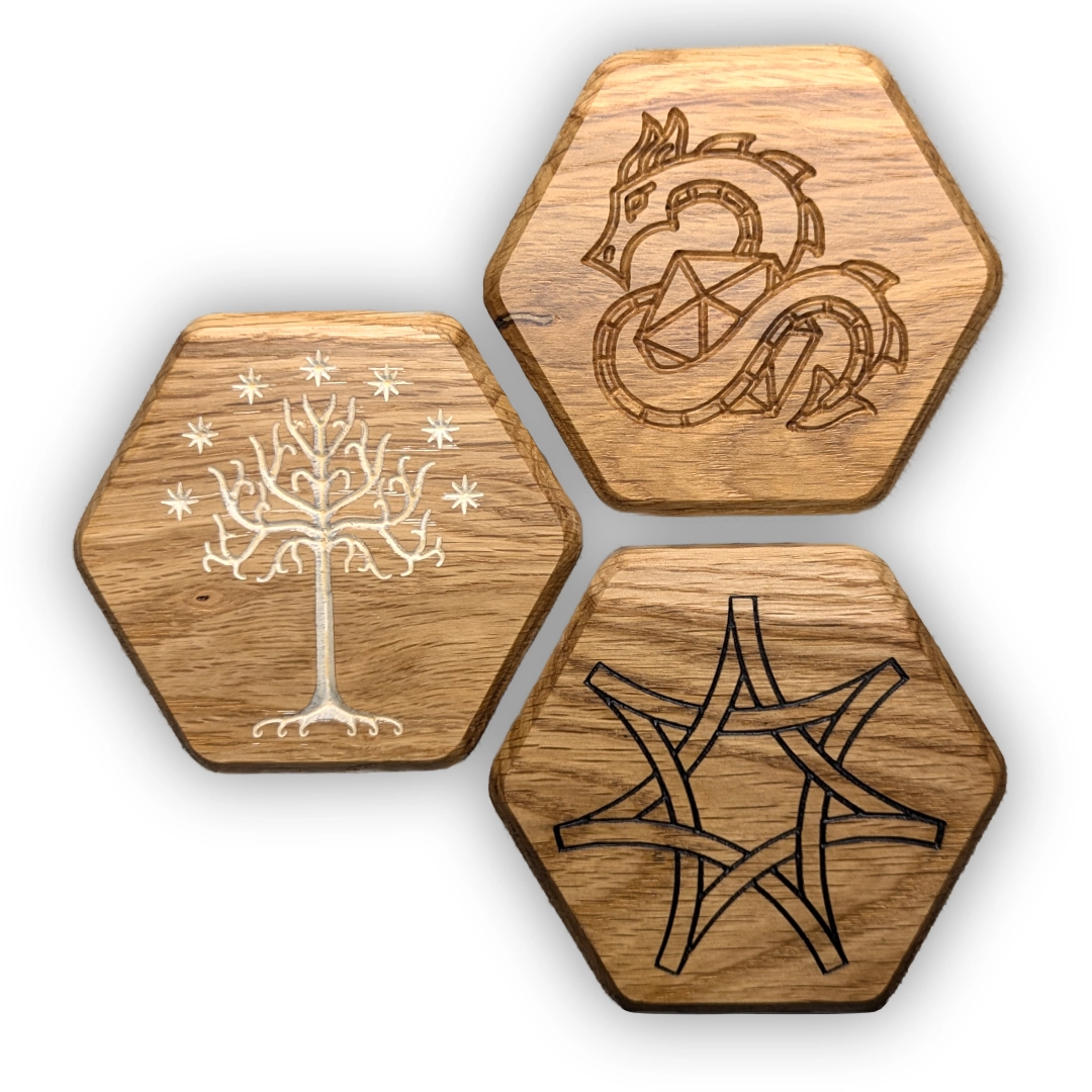 Three hexagonal box lids, each with a different engraving. One shows the White Tree of Gondor; one, a dragon curled around a twenty-sided die; one, a Celtic knot in the shape of a seven-pointed star.