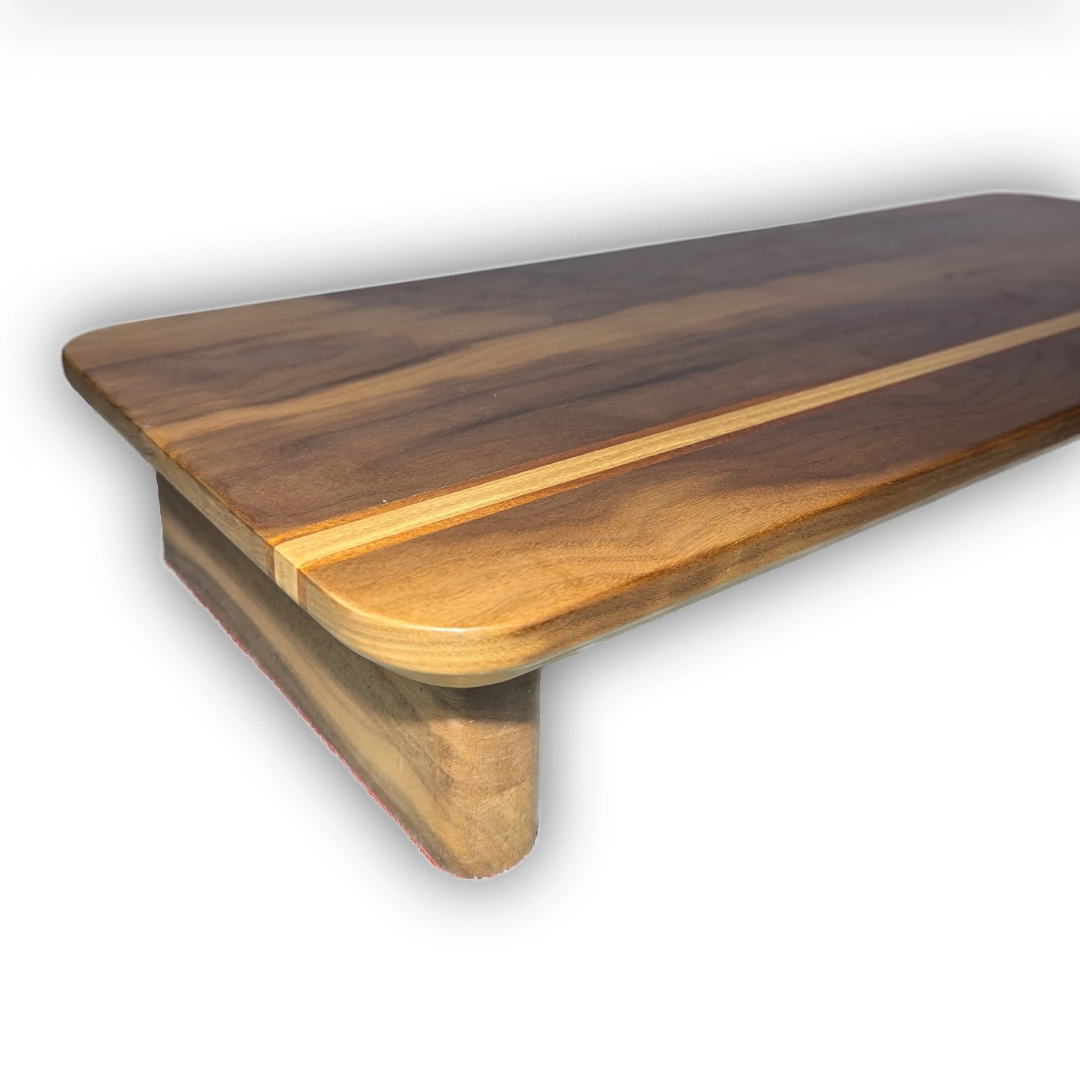 A wooden monitor stand with a band of light wood sandwiched between thin strips of orange wood, running across the front